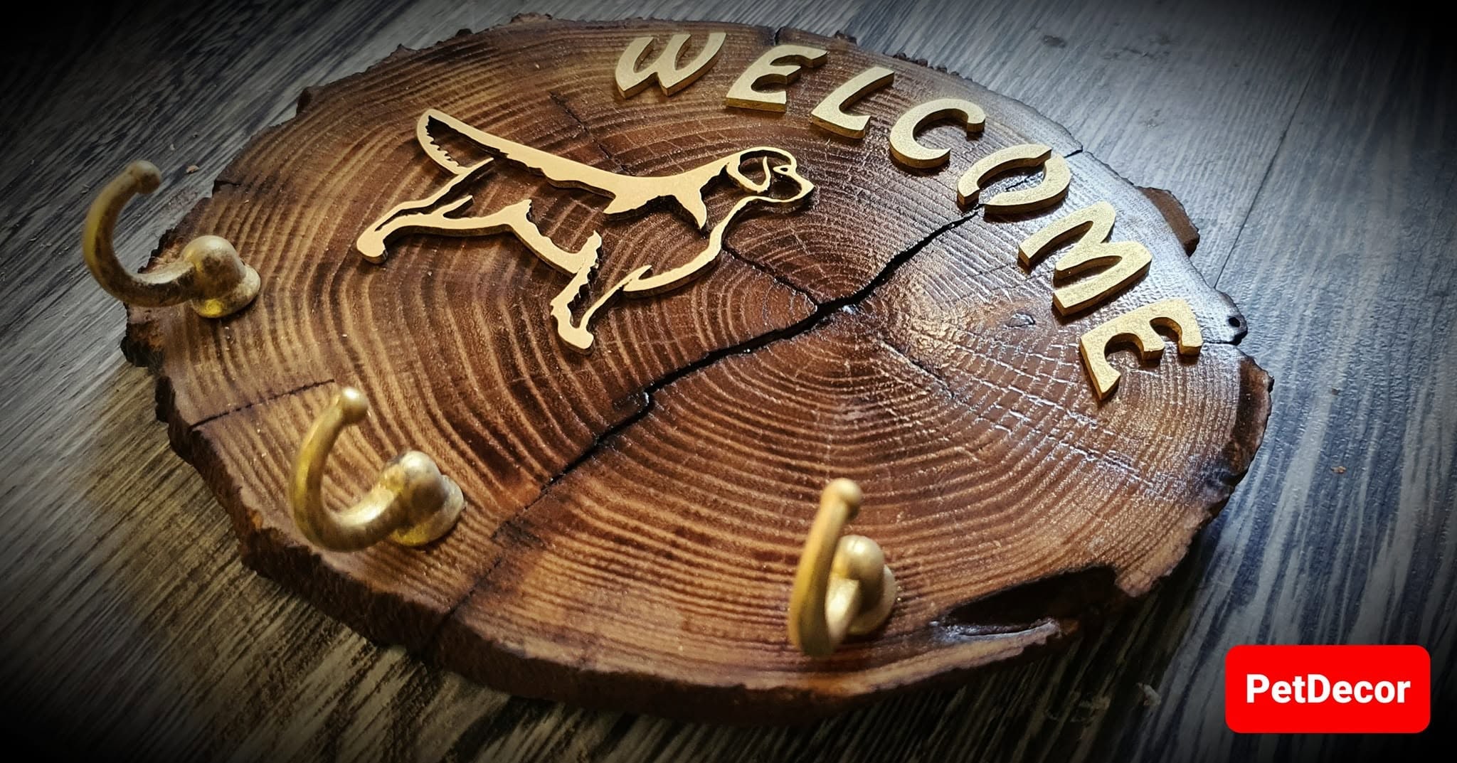 Angled view of the acacia slab key holder with Welcome lettering, brass silhouette and three hooks