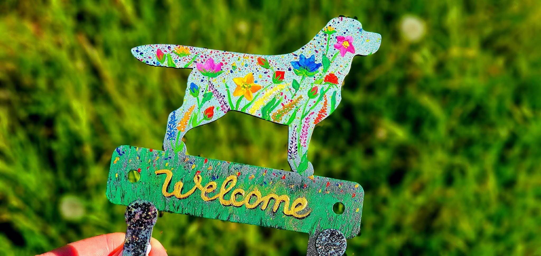 Floral dog hanger with Welcome lettering against a grass background