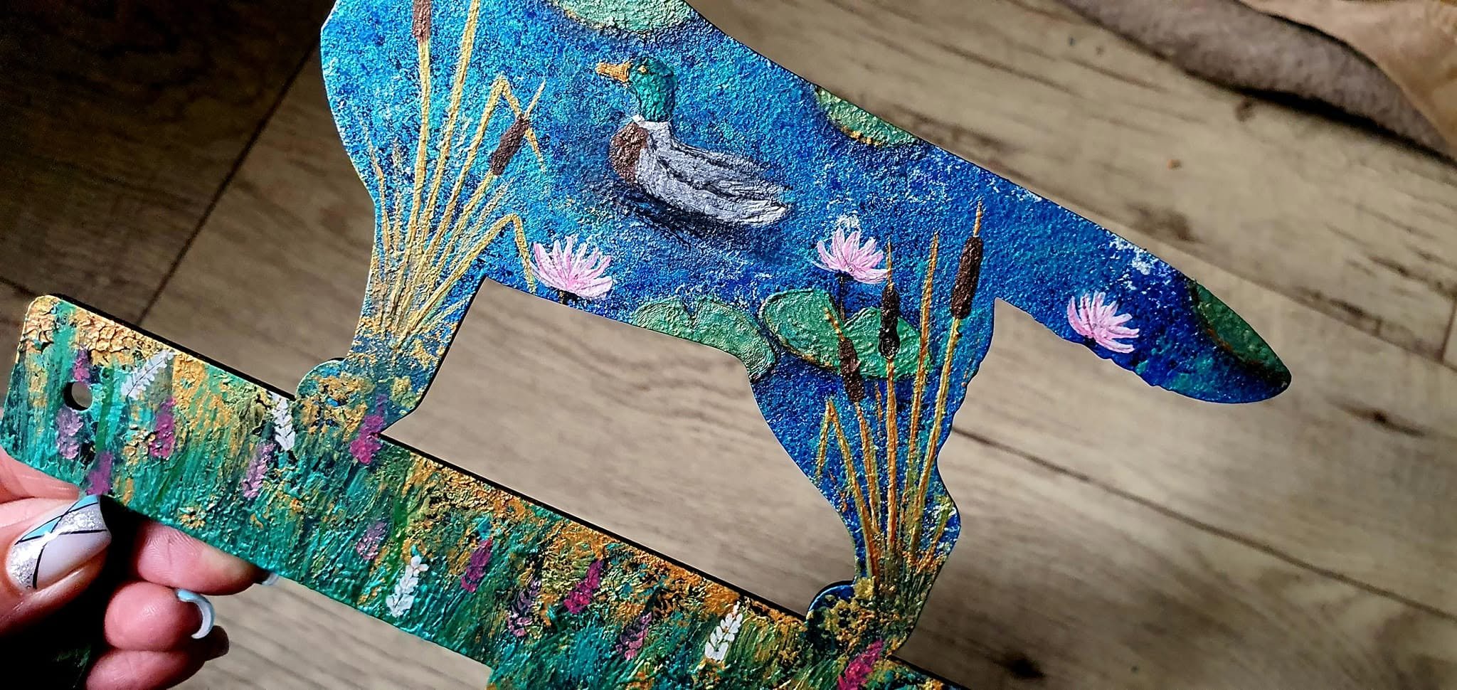 Metal dog-shaped hanger with blue painting and a pond scene