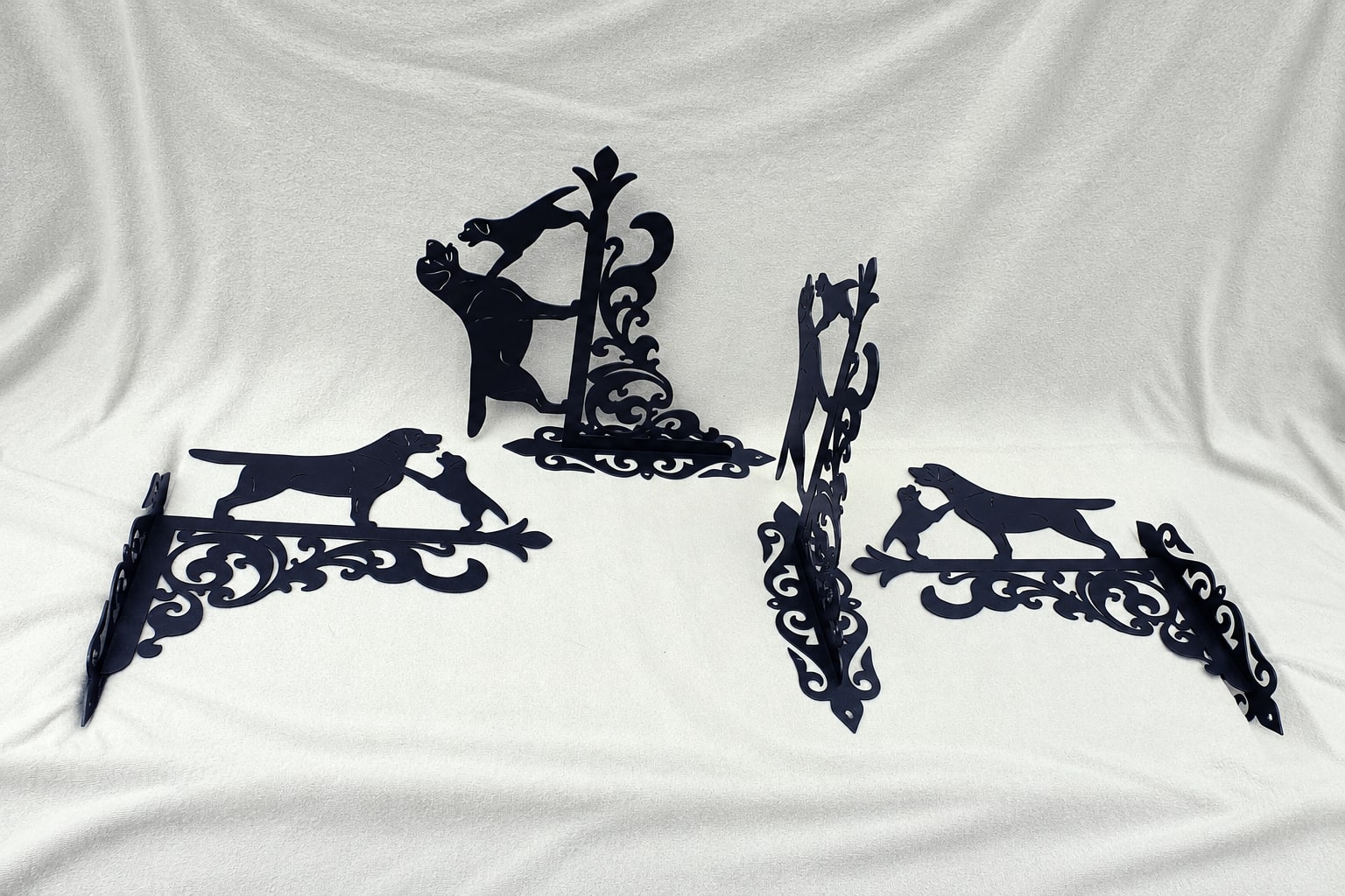 Four black Mother and Puppy brackets on light fabric
